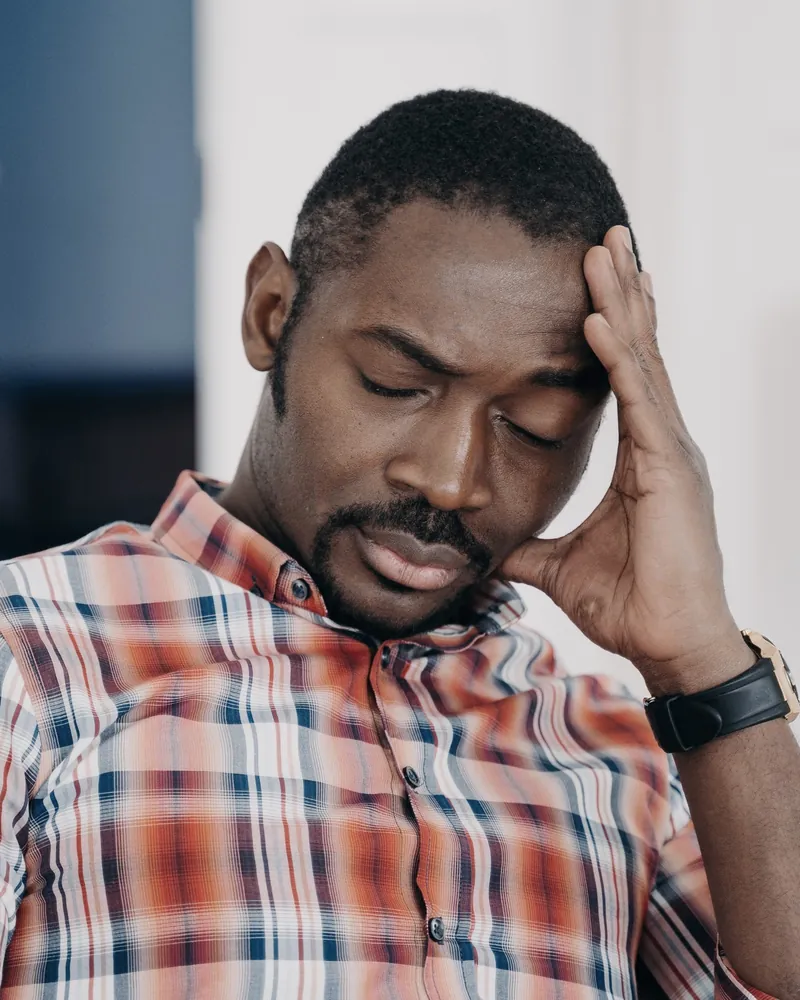 A man with his eyes closed, resting his head on one hand